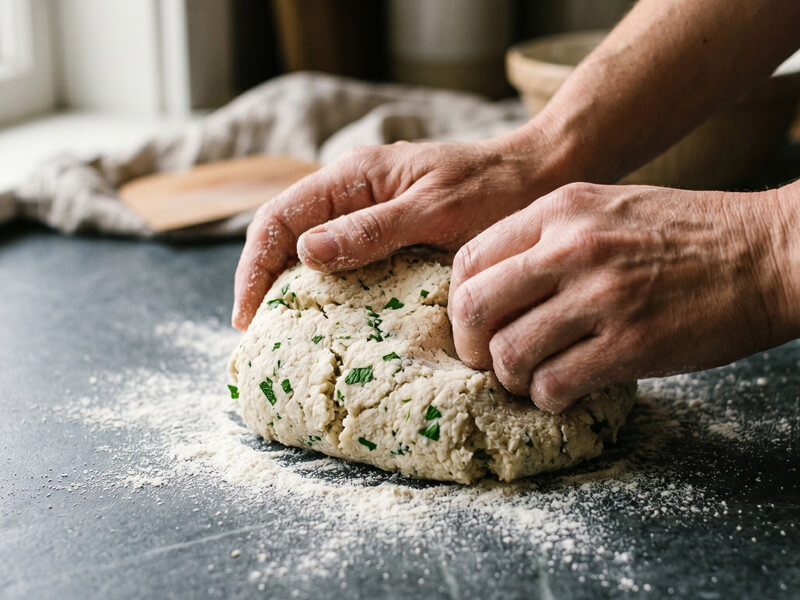 Hands kneading keto bread stick dough made from almond flour and mozzarella into a smooth ball.